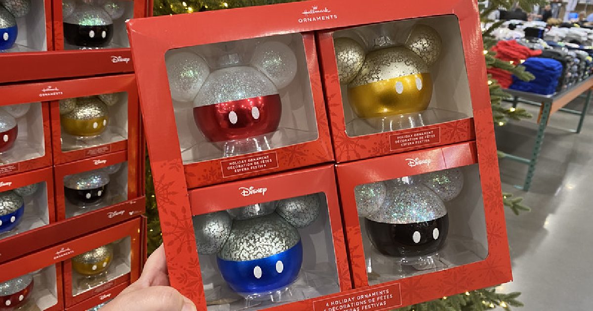 hand holding box of four colorful mickey mouse themed ornaments