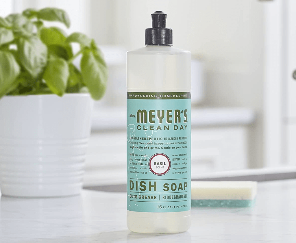 bottle of Mrs. Meyer's Dish Soap next to a basil plant
