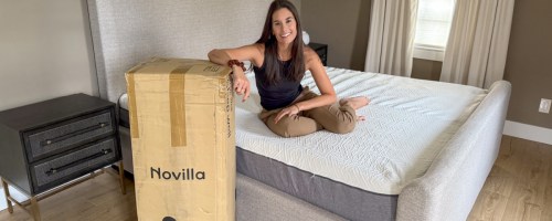 Woman sitting on a Novilla Matress with her arm resting on the Novilla packaging