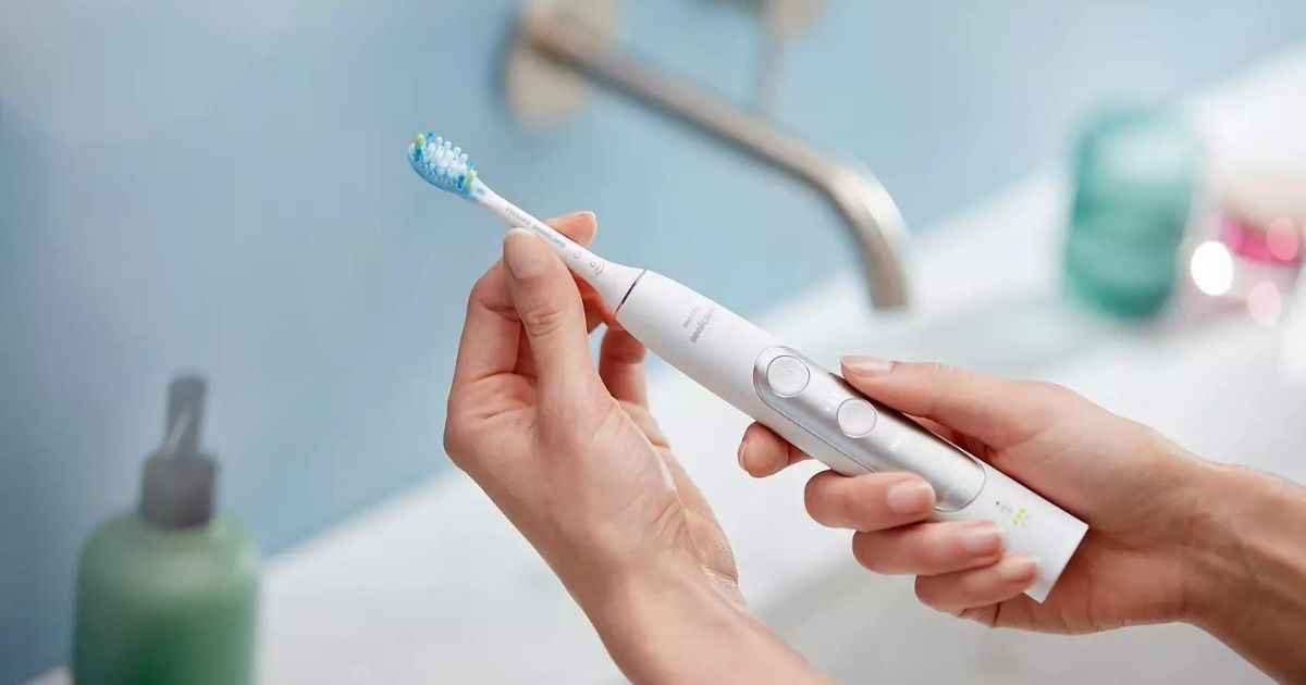 hands holding white Sonicare toothbrush