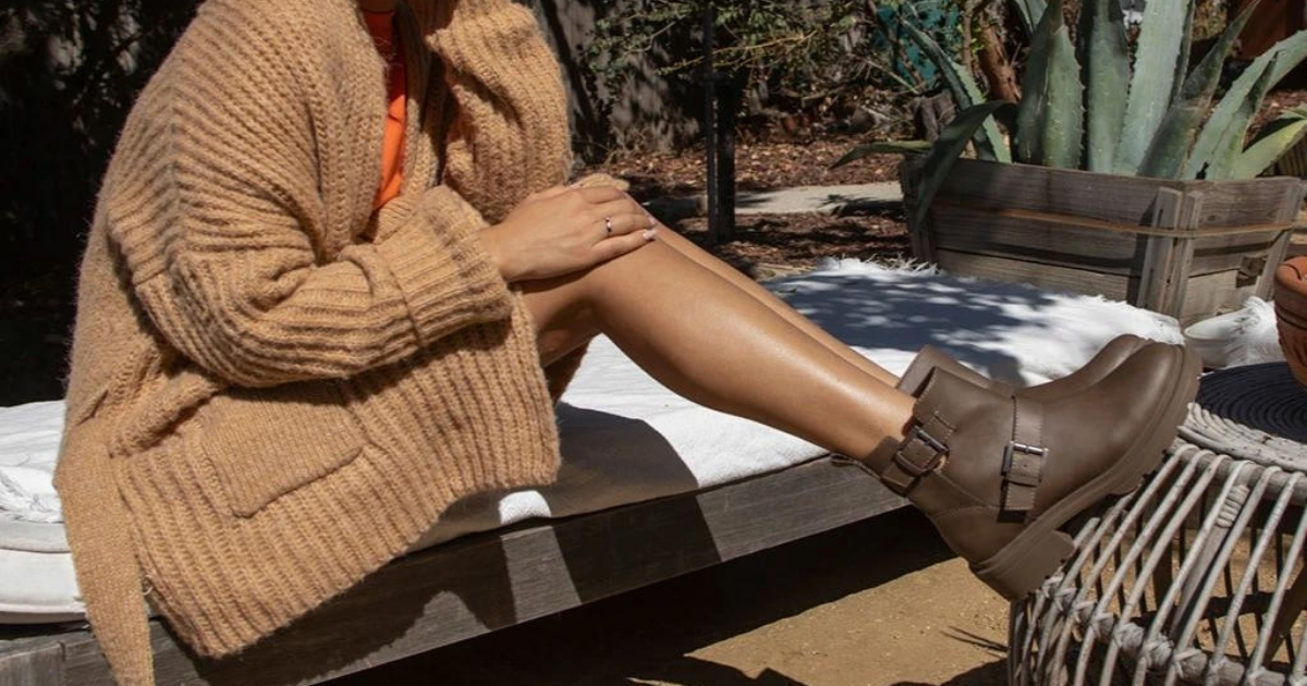 Person sitting on a bench wearing a brown cardigan and brown boots