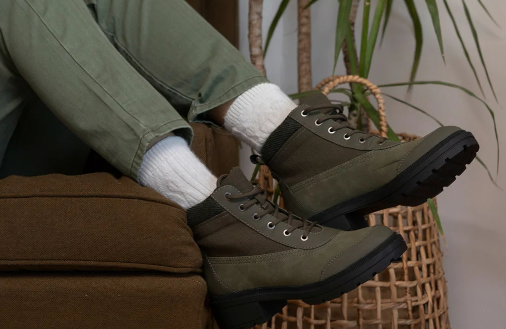 Person wearing a pair of olive green boots and pants and sitting on a brown sofa