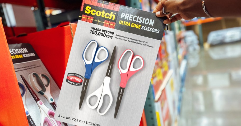 hand grabbing a set of Scotch Precision Ultra Edge Scissors in store