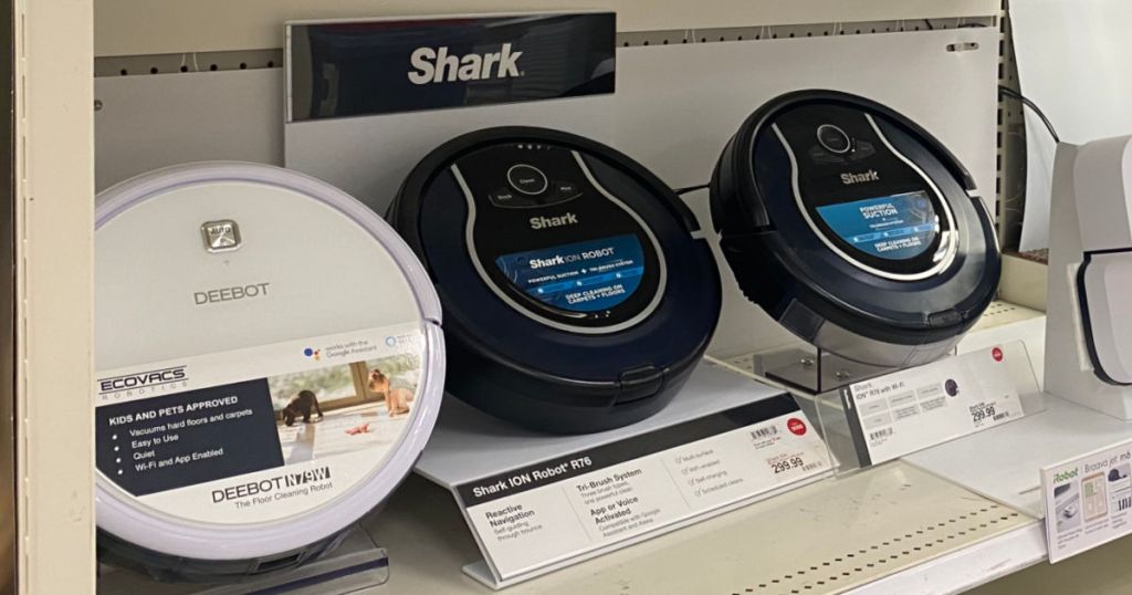 two black and one white robot vacuums on shelf 