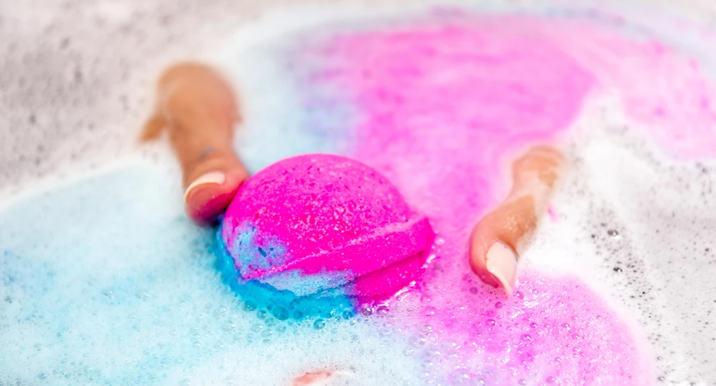 hands holding a bath bomb in the tub