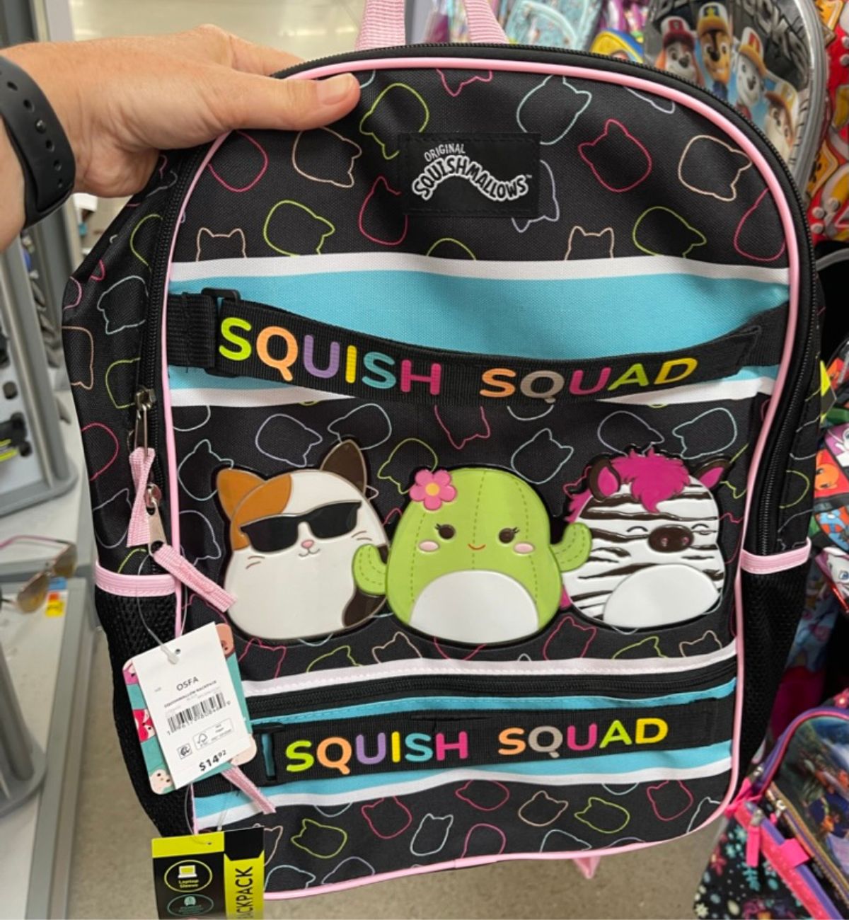 a womans hand holding a Squishmallows backpack