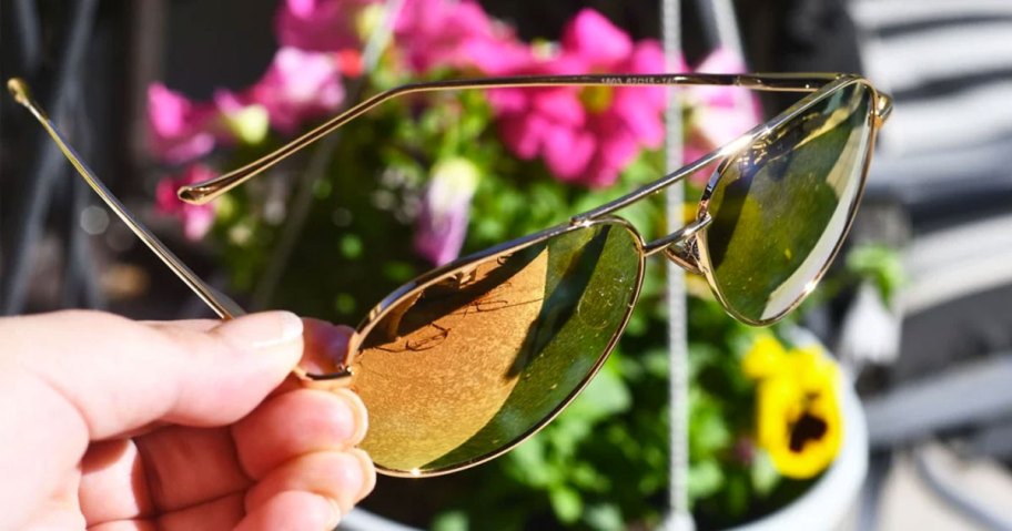 holding pair of sunglasses