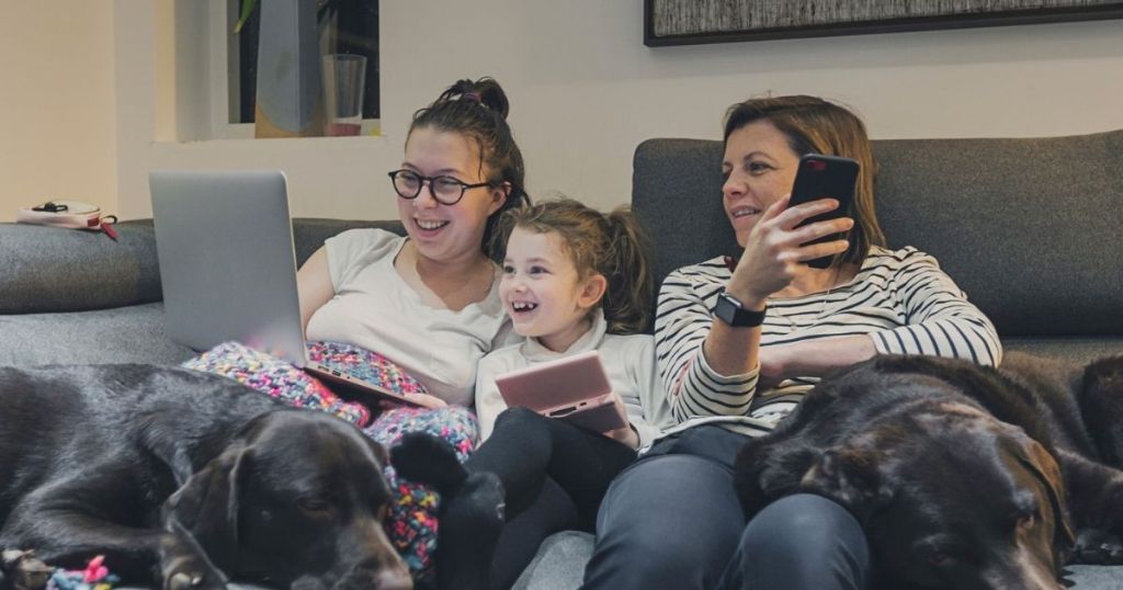 woman and kids sitting on couch looking at smart devices