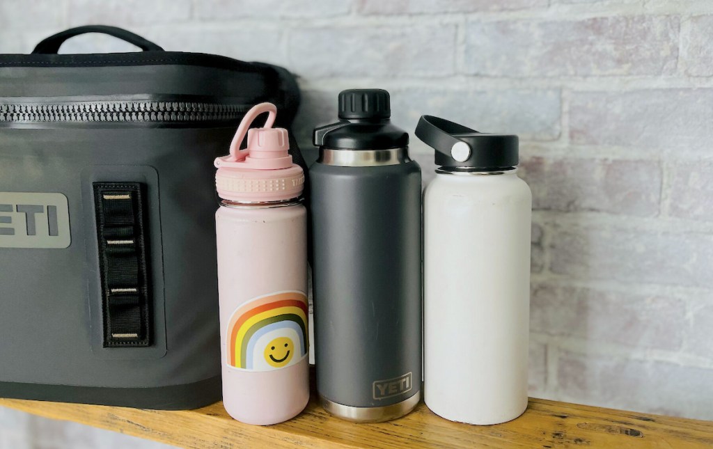 pink gray and white reusable best water bottle brands on wood bench next to yeti cooler