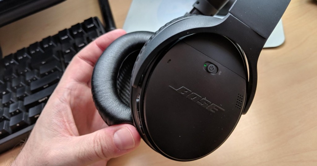 holding a pair of Bose headphones
