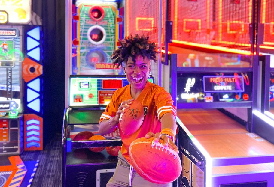woman holding footballs in dave and busters sports bar