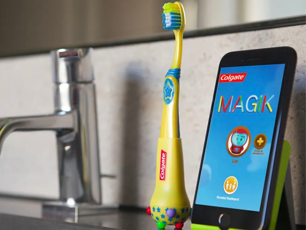 colgate magik toothbrush next to phone on sink