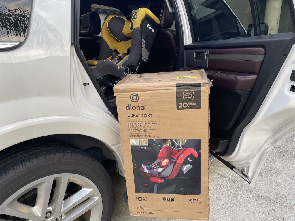 diono car seat box sitting on ground next to open car door