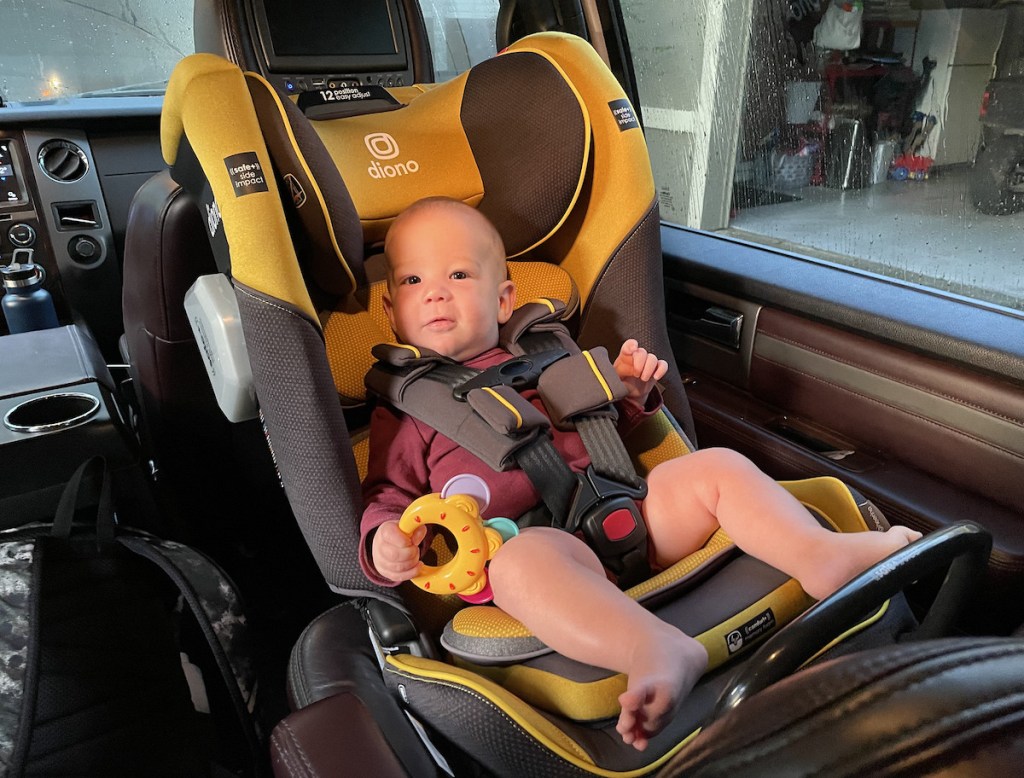 boy sitting in yellow and gray car seat inside of car
