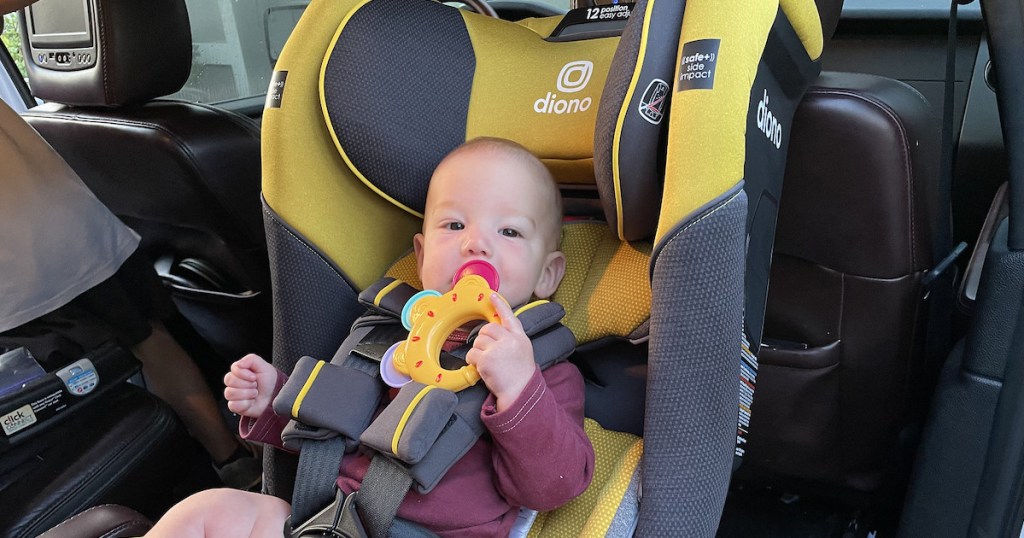 baby boy in yellow and gray diono car seat in car chewing on toy