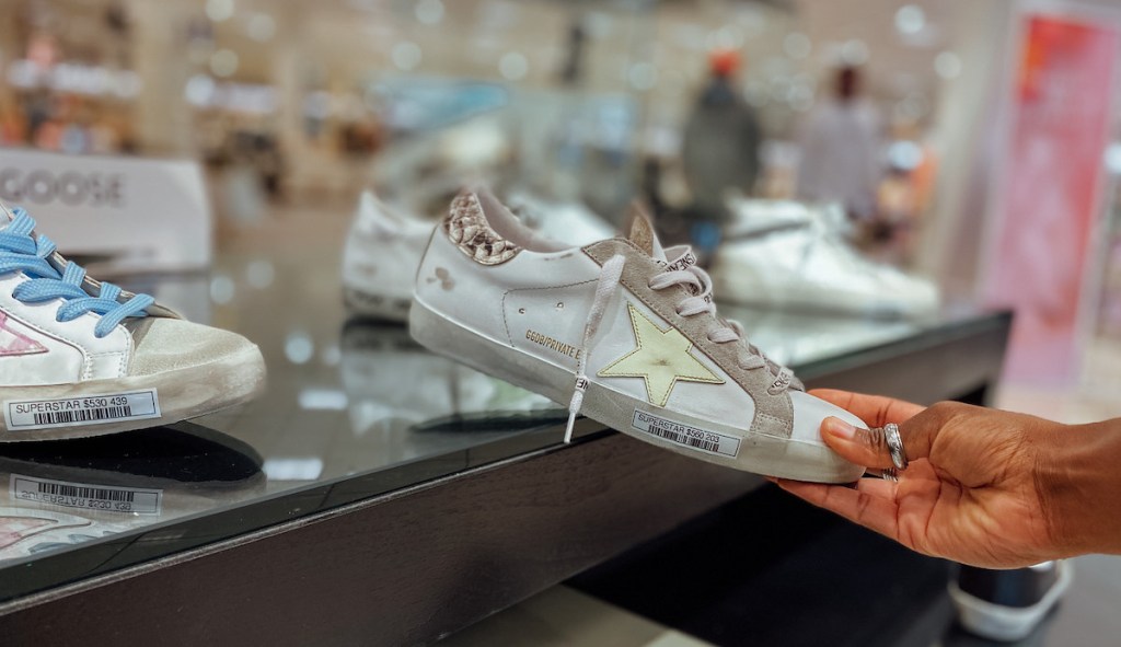hand holding a golden goose sneaker in store