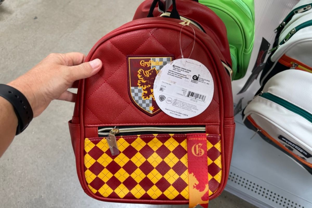 a womans hand holding up a gryffindor mini dome backpack