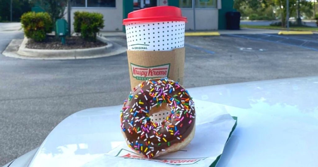 Krispy Kreme donut leaning against coffee cup