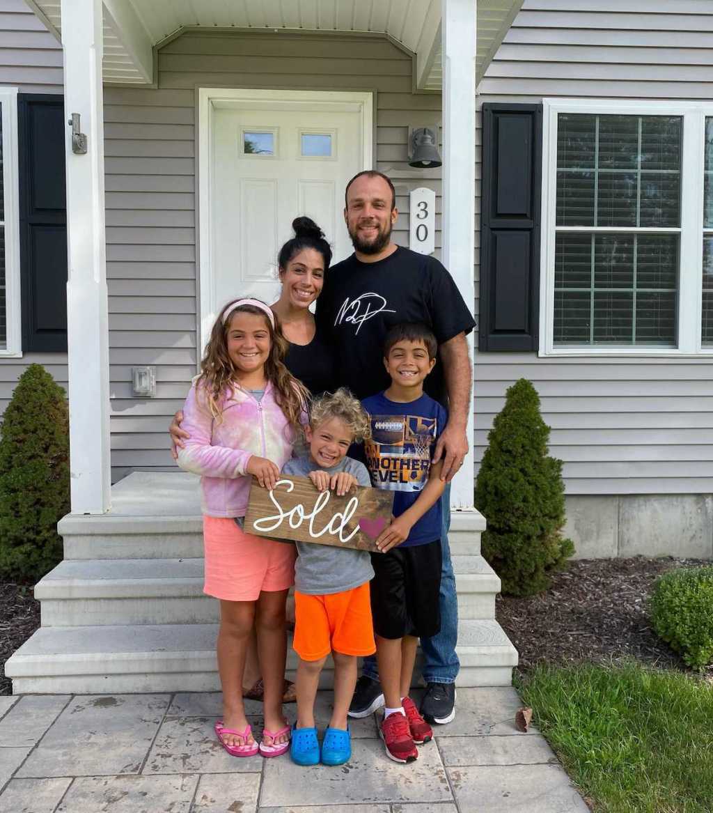 family standing in front of house with sold sign 