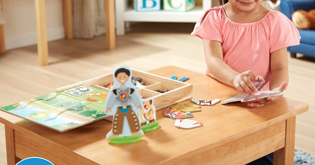 girl playing with a melissa doug magnetic dress up dolls set on a table