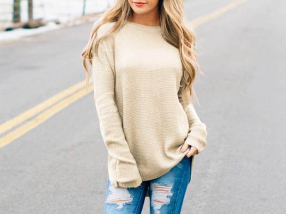 woman on street wearing jeans and sweater