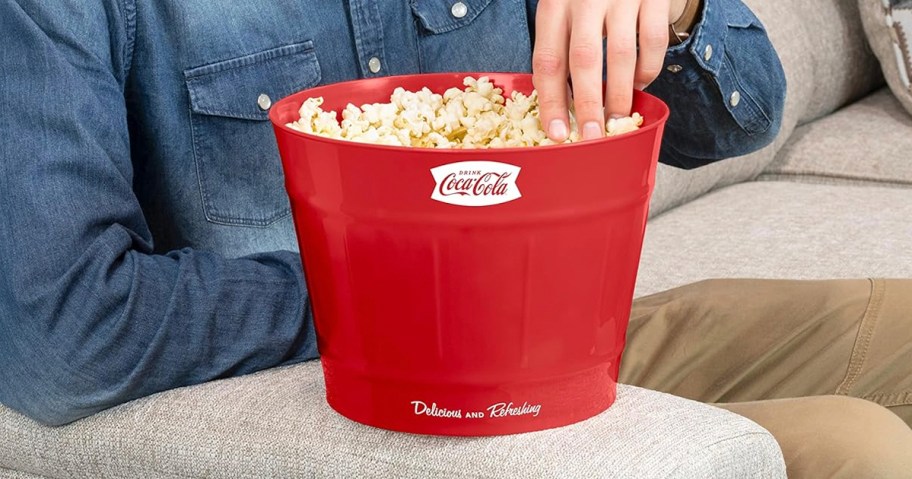 hand taking popcorn out of coca cola red bucket