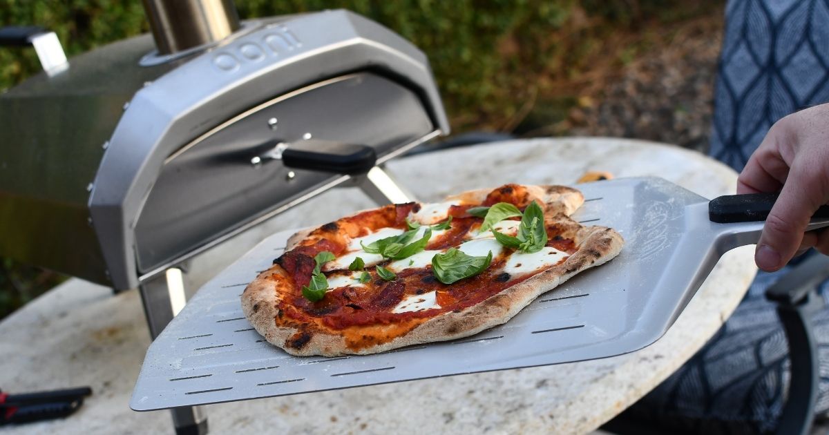 pulling a homemade pizza out of an Ooni Karu oven