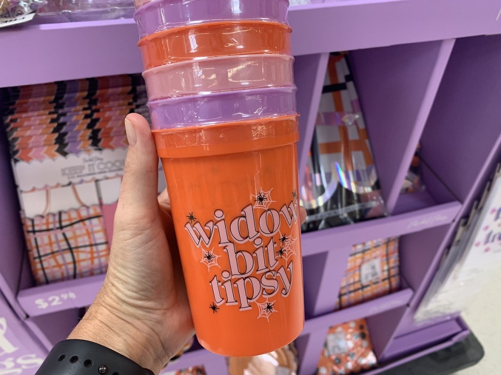 holding a stack of Halloween cups