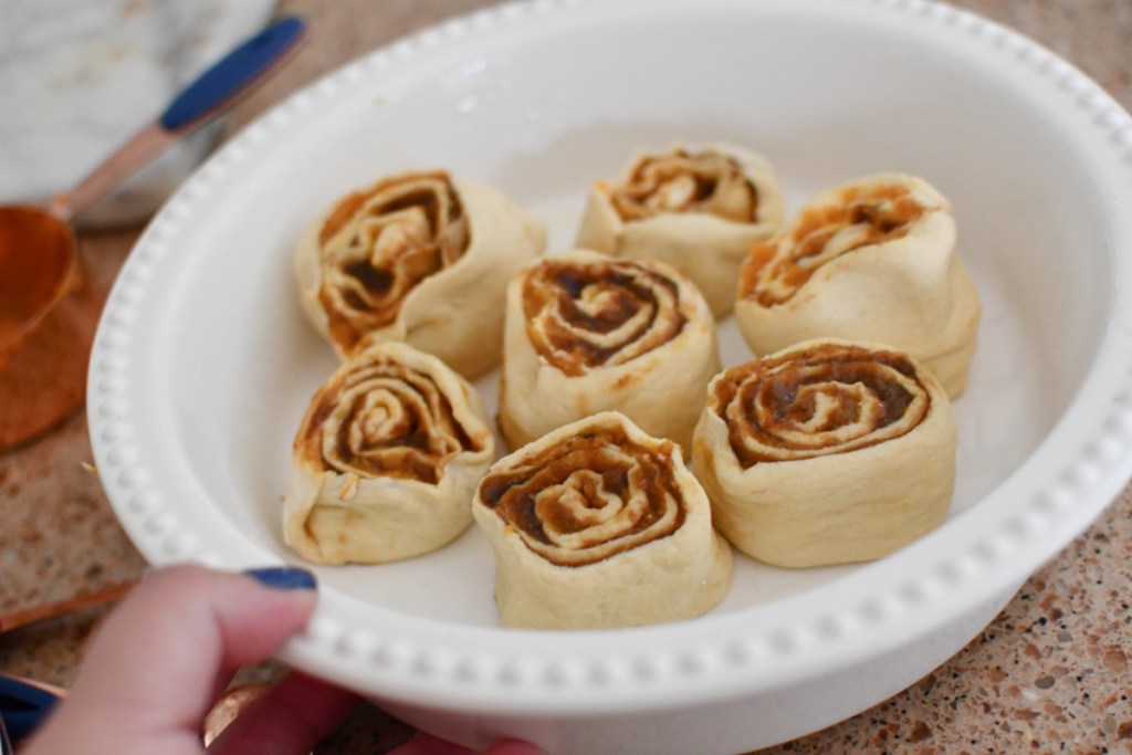 placing cinnamon rolls in a baking pan
