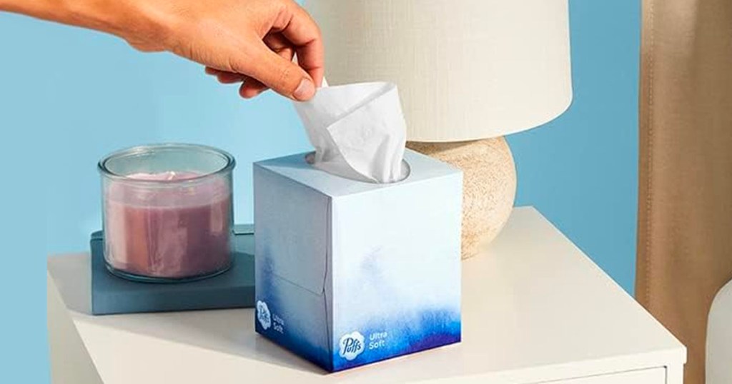 hand pulling tissues out of box on table