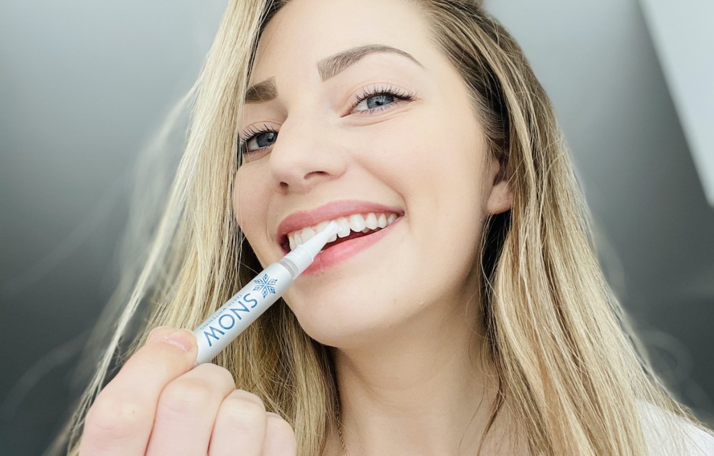 woman holding whitening gel tube to tooth