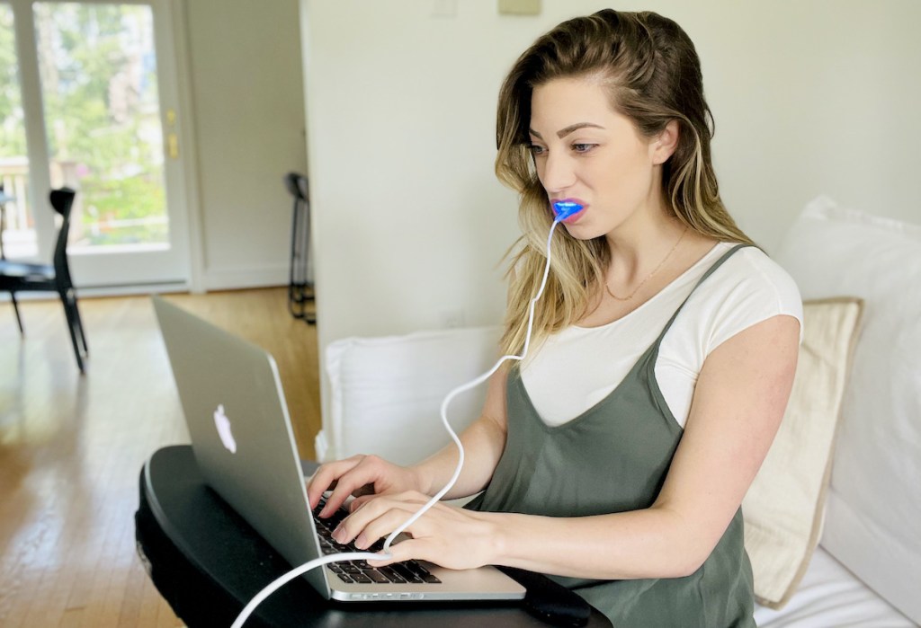 woman typing on laptop wearing snow teeth whitening 