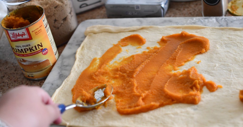 spreading pumpkin puree on crescent roll dough
