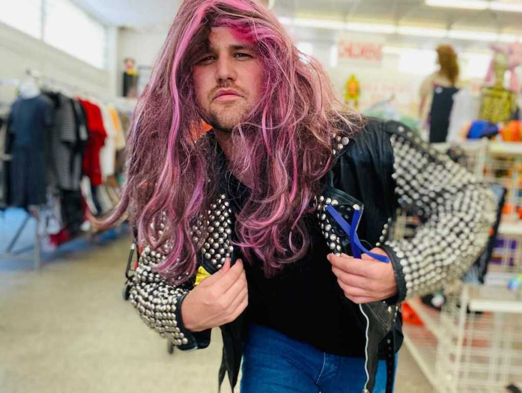 man wearing purple wig and black studded jacket in store