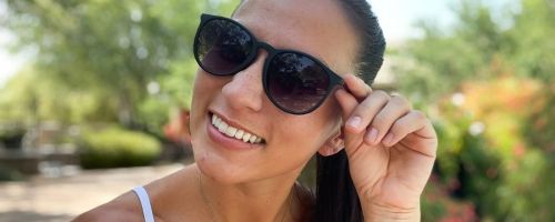 woman smiling at the camera wearing sunglasses