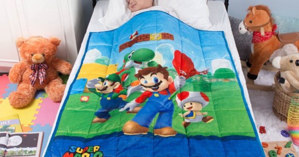 kid in bed under blanket with Super Mario on it
