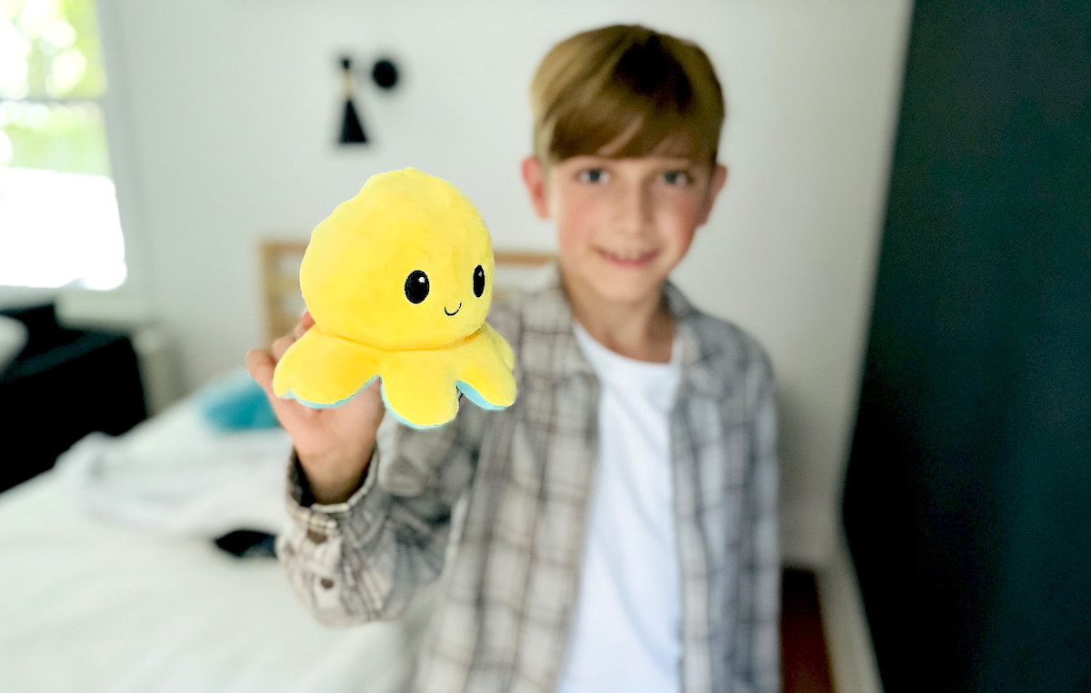 boy holding yellow stuffed octopus in hand