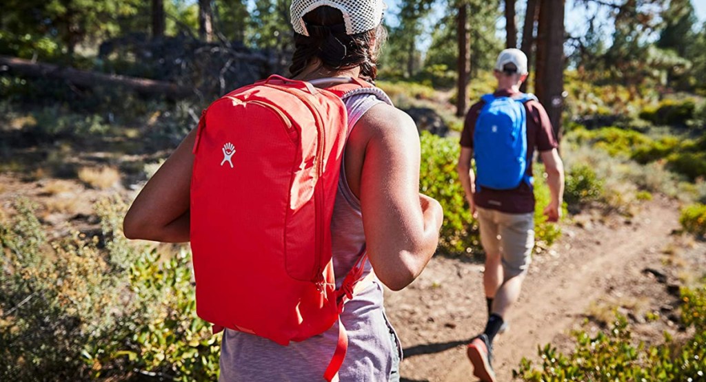woman and men walking with hydration backpacks in colors red and blue