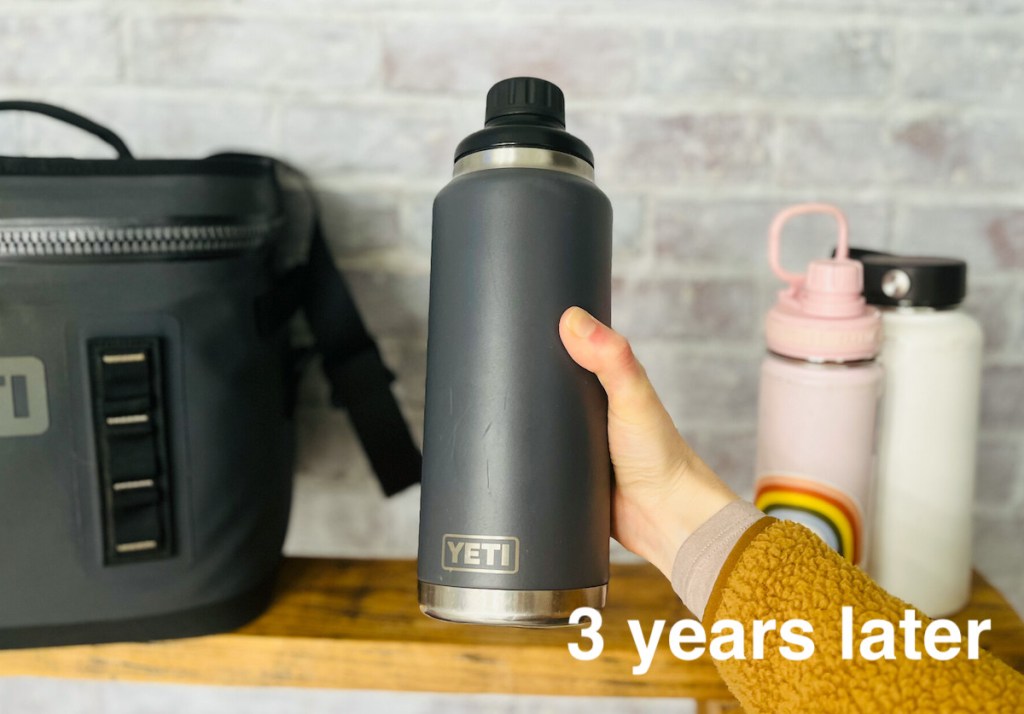 hand holding charcoal colored yeti water bottle with three year update