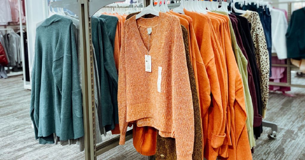 orange and teal sweaters hanging on rack 