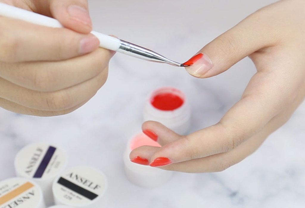 woman applying red polish to nails