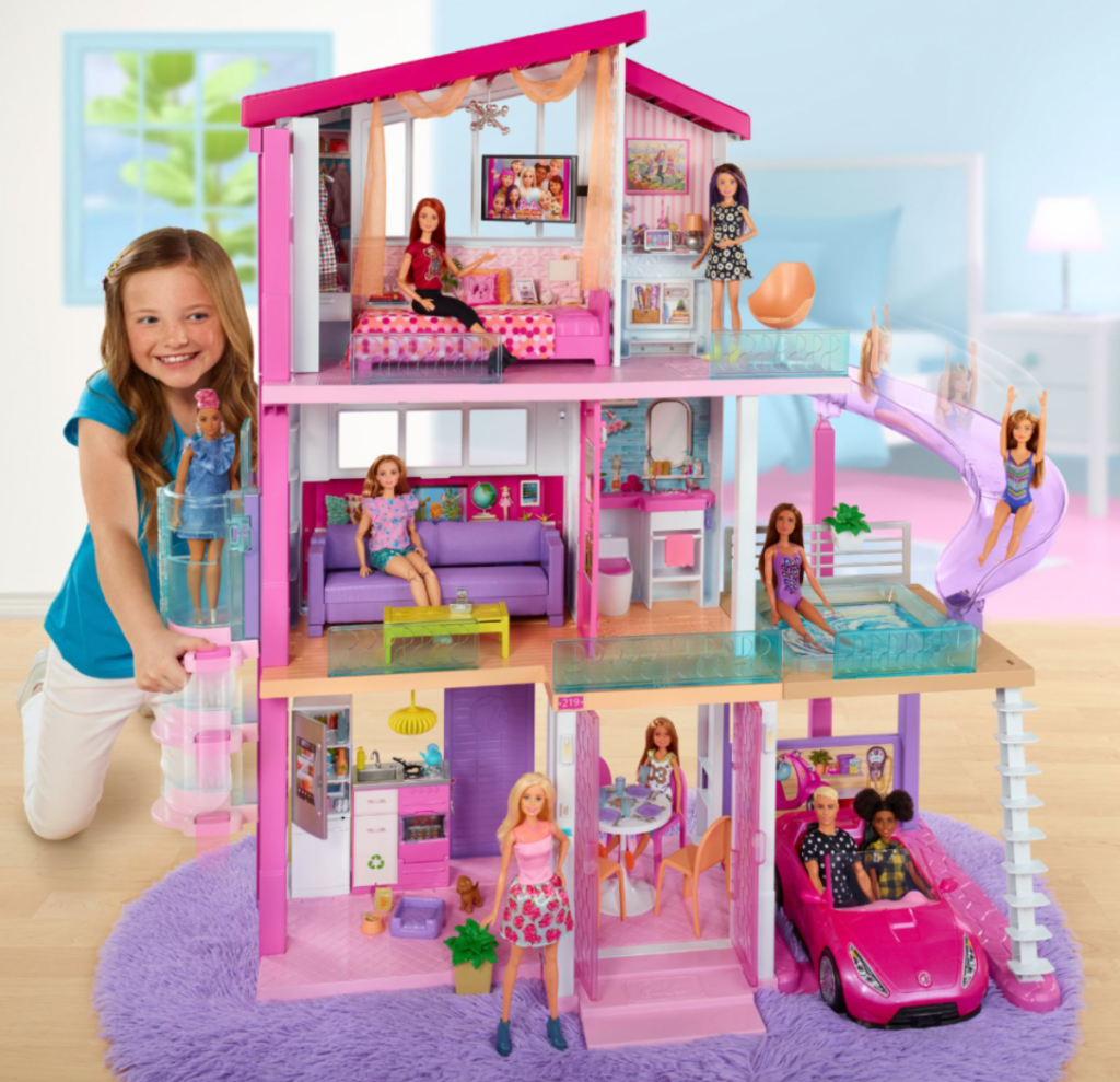 girl next to a Barbie dreamhouse