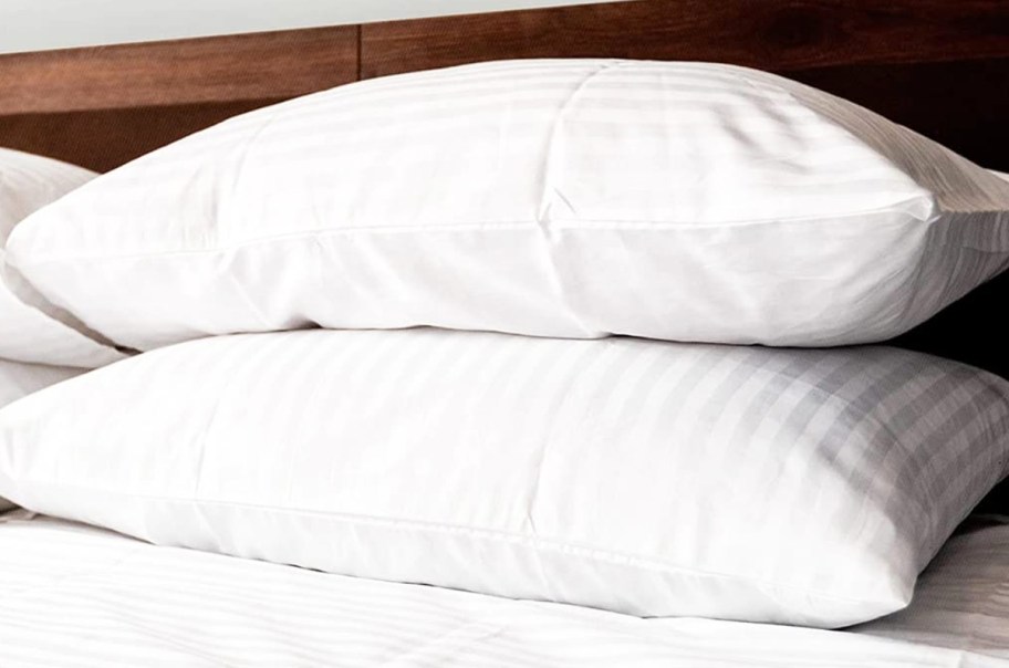 two stacked white pillows on a bed
