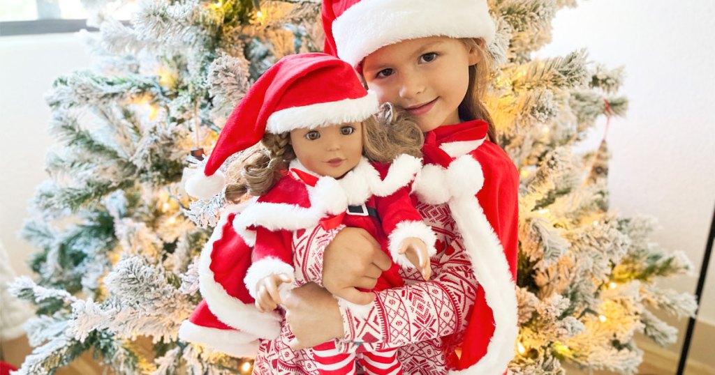 girl holding doll in matching santa set