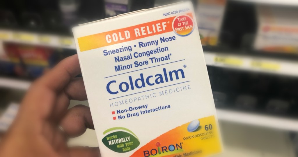 hand holding white and yellow box of cold medicine 