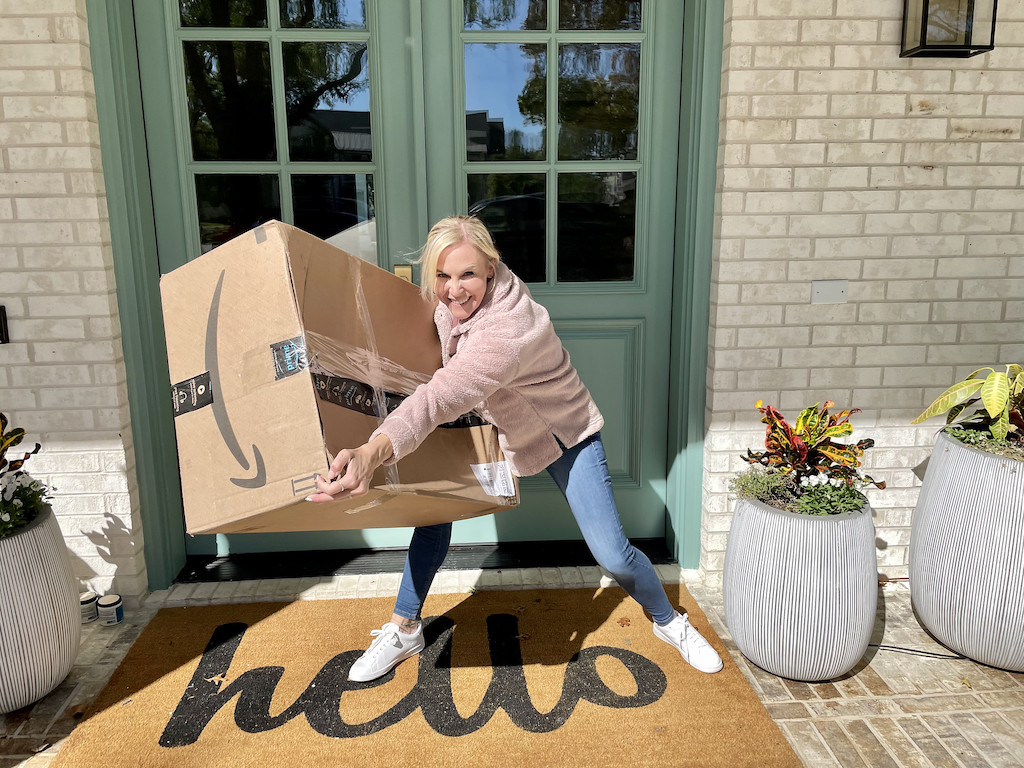 woman holding large Amazon box on front porch 