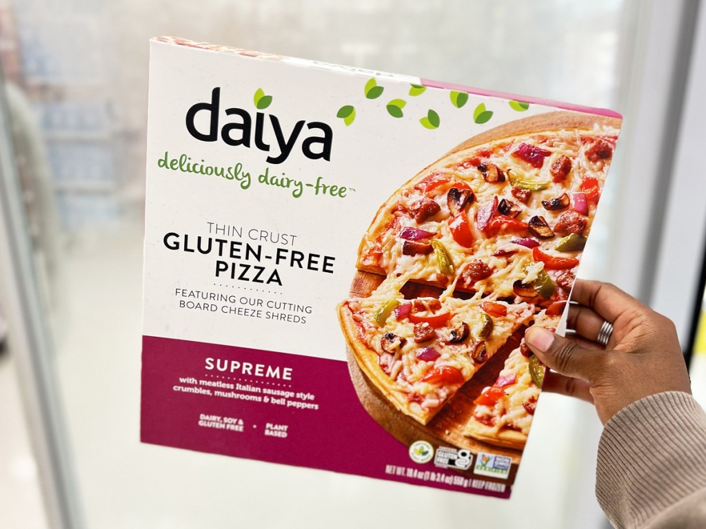 hand holding up a supreme Daiya frozen pizza