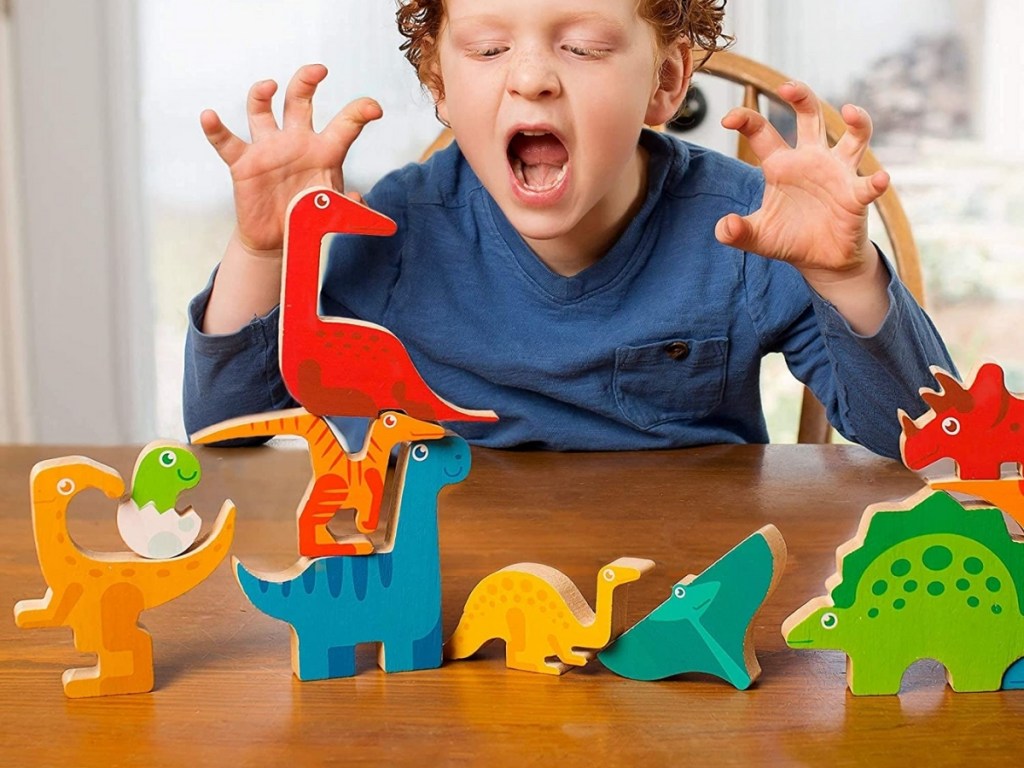 child playing with wooden dinosaur puzzle pieces
