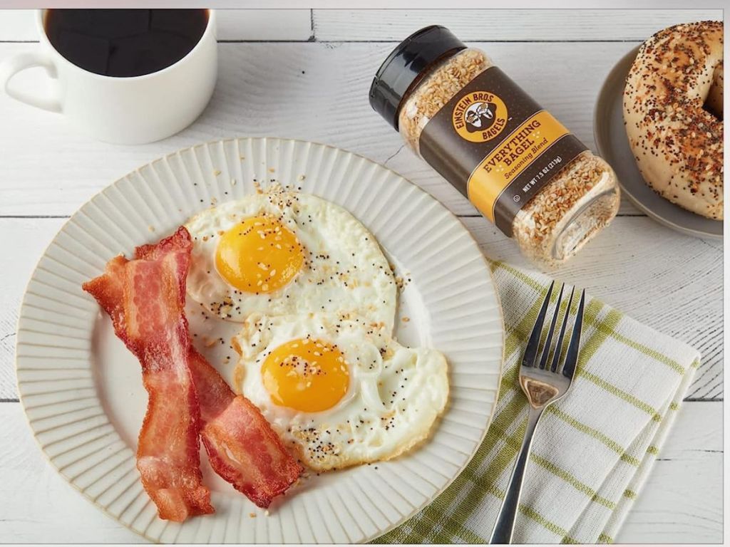 Einstein Bros Bagel Seasoning next to a plate of eggs and bacon
