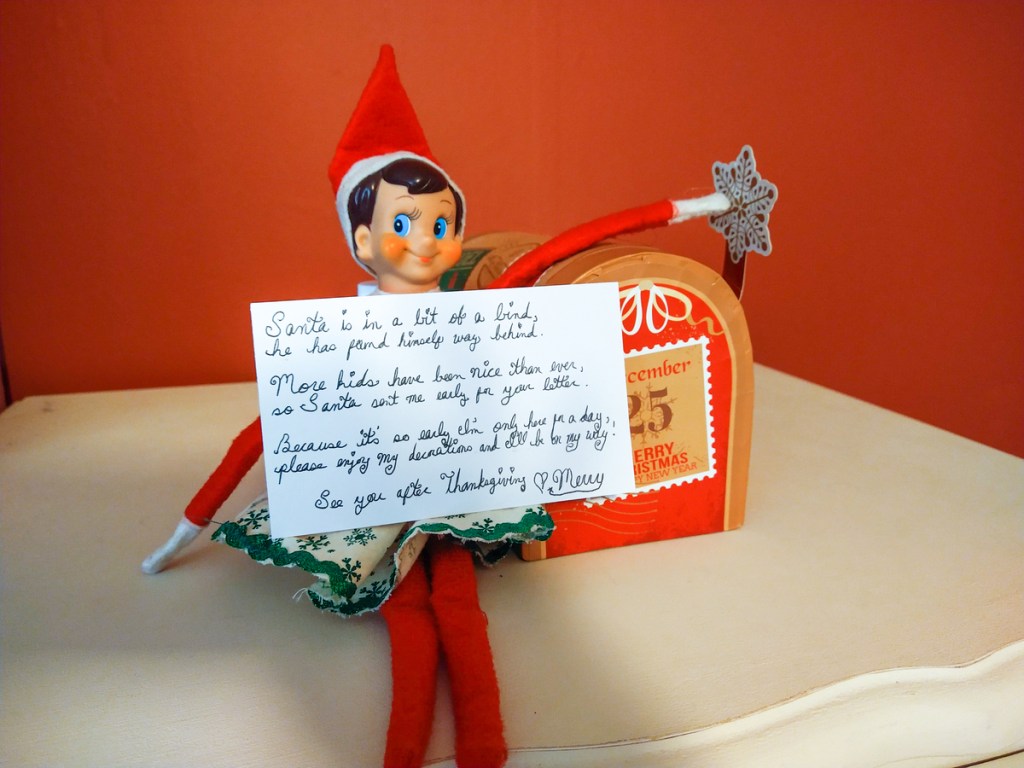 merry the elf on a shelf holding a card